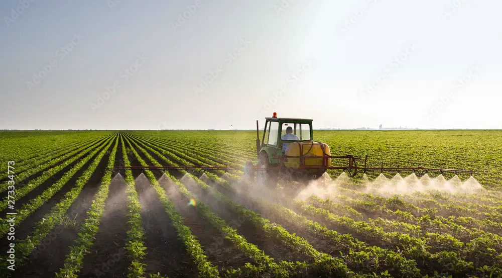 Tractor spraying soybean field